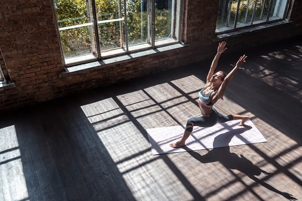 Una mujer fitness haciendo yoga deportivo en un amplio lugar con ventanas